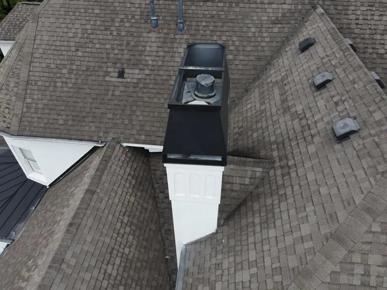 The old roof up close, shingles worn flat around the chimney